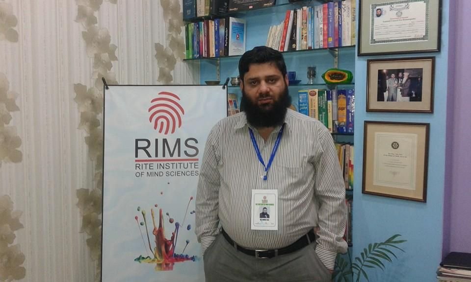 Dr. Ahmed Ejaz beside the Rite Institute of Mind Sciences banner