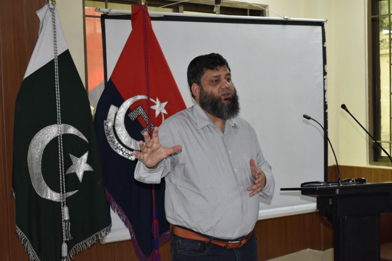 Dr. Ahmed Ejaz leading a training session beside the Pakistan flag