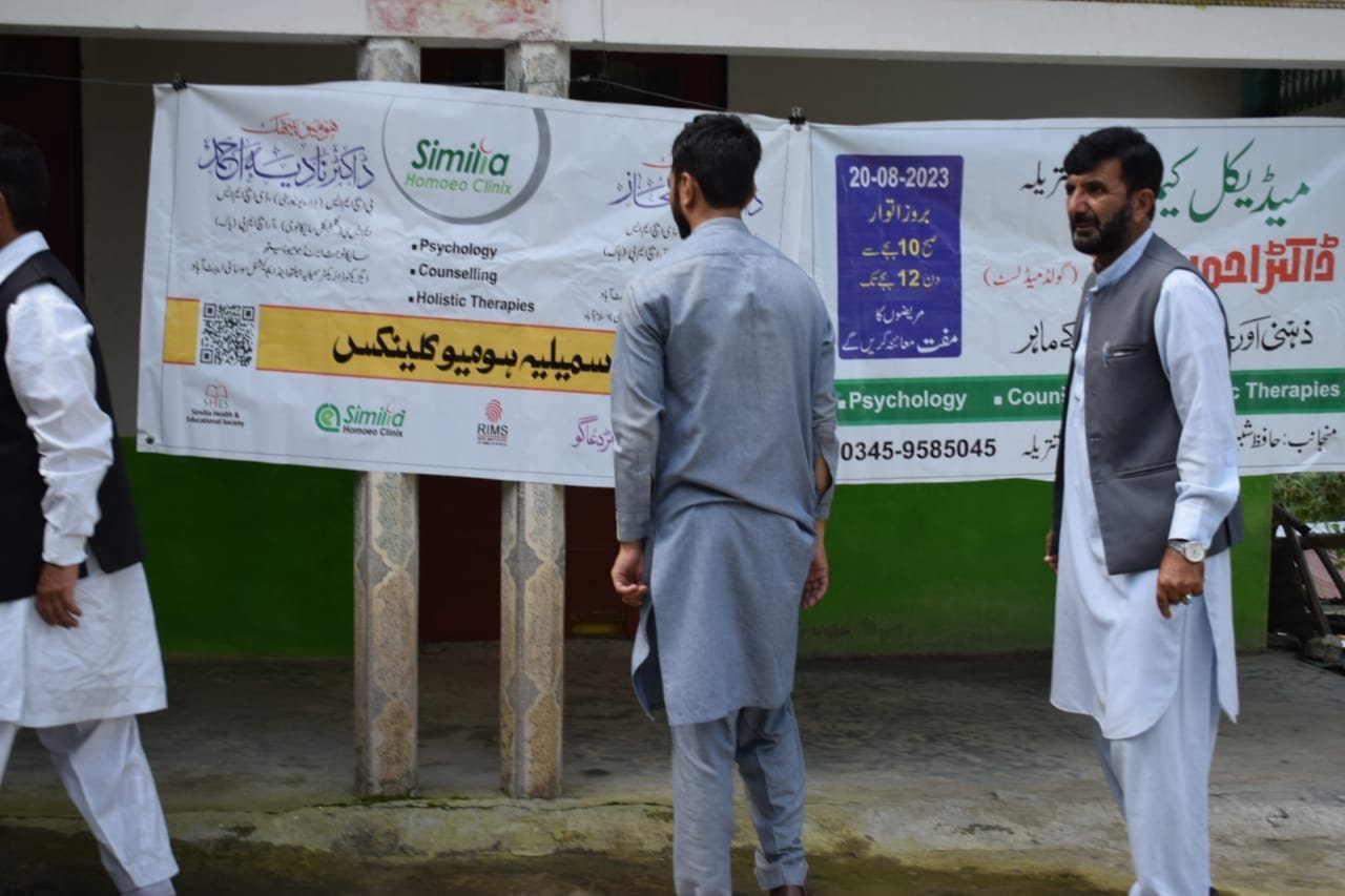 Volunteers beside the Similia and medical camp banners