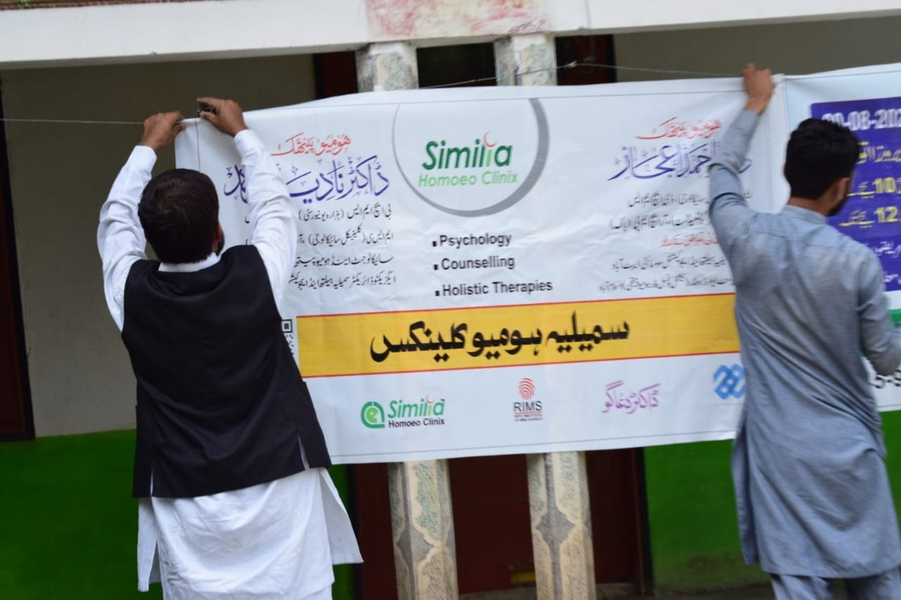 Volunteers hanging the Similia Homoeo Clinix camp banner